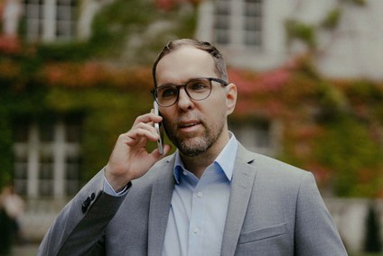Rechtsanwalt David Geßner telefoniert vor herbstlichem Efeu, Einordnung zu inoffiziellen Fanartikeln für rbb24
